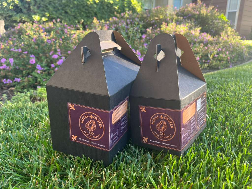 Royal Oyster Co. branded gift boxes on a sunny South Bay lawn